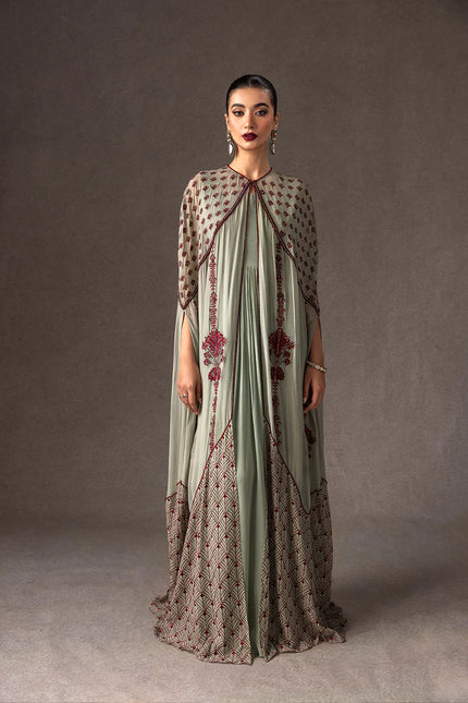 Woman wearing a long, patterned dress against a plain background