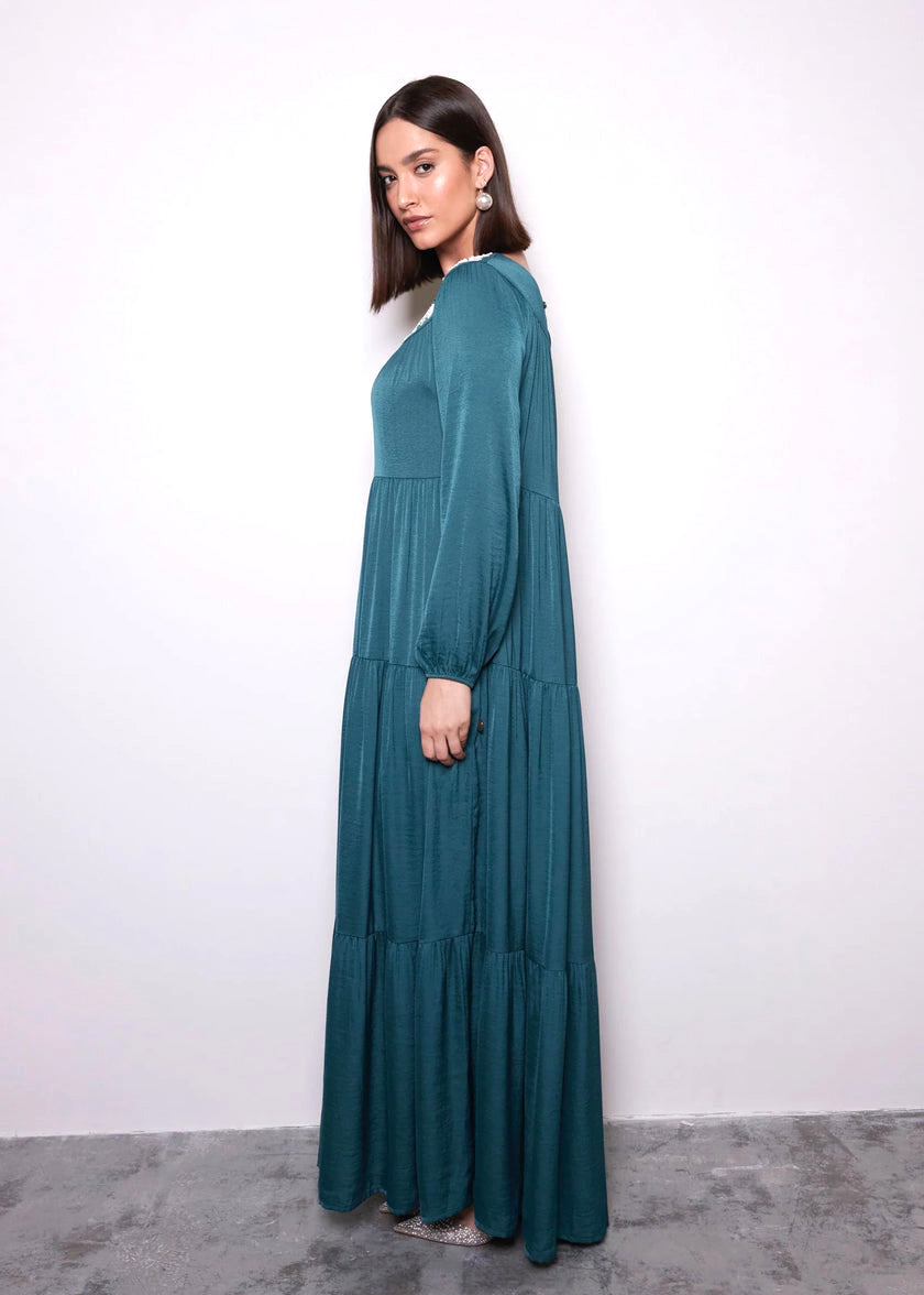 Woman wearing a teal long-sleeve dress against a white background