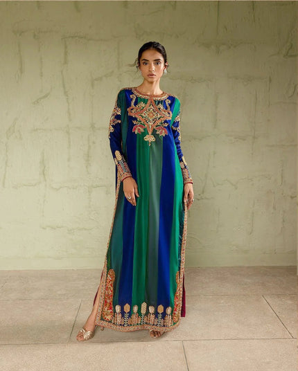 Woman wearing a long, colorful dress with intricate patterns against a neutral background