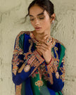 Woman wearing a traditional embroidered outfit with a neutral background